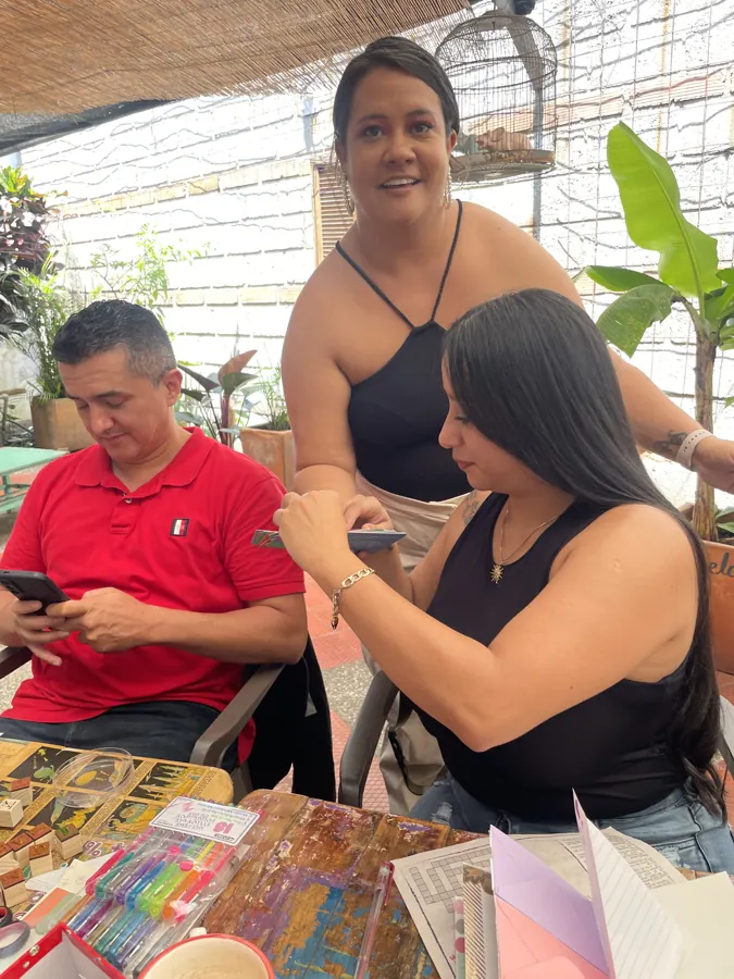Sandra acompaña a dos participantes que escriben